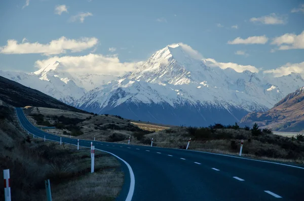 Sneeuw bedekt Mount Cook met weg op de voorgrond amd blauwe lucht en witte wolken, South Island, Nieuw-Zeeland — Stockfoto