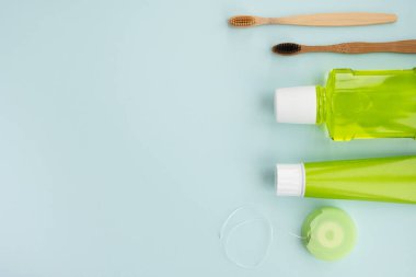 Bambu diş fırçaları ve açık mavi arka planda ağız temizliği ürünleri. Diş temizliği konsepti. Üst görünüm, düz görünüm, kopyalama alanı