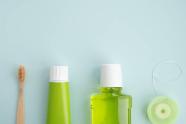 Bambu diş fırçası ve açık mavi arka planda ağız temizliği ürünleri. Diş temizliği konsepti. Üst görünüm, düz görünüm, kopyalama alanı