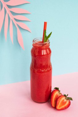 Cam şişede çilekli smoothie. Pastel arka planda çilekli yaz içeceği. Minimum trend kompozisyonu. Yakın, dikey