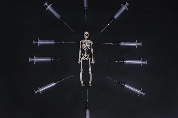 Social advertisement. Death from drugs. Skeleton on a black background with syringes.