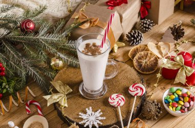 Noel ve yeni yıl içkileri cam bardakta, masanın üstünde, üzerinde hediyeler, Noel kurabiyeleri, mumlar, şekerler olan tahta bir stantta. Tatil içeceği tarifleri için.