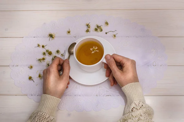 Té con manzanilla. Chica sostiene una taza con té sobre un fondo blanco, vista superior. Para inmunidad, para resfriados, prevención — Foto de Stock