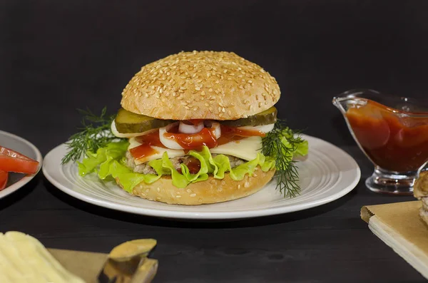 Připravený hamburger se ingrediencemi na talíři na černém dřevěném pozadí. Pro reklamu, menu. — Stock fotografie