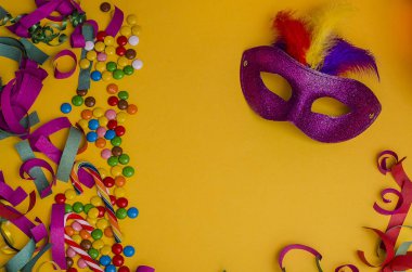 Karnaval. Fotokopi alanı olan şenlikli bir arka plan. Karnaval maskesi mor, sarı arka planda tüyleri var. Süslü, çok renkli tatlılar. Mardi Gras 'da. Brezilya Dili.