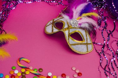 Karnaval. Fotokopi alanı olan şenlikli bir arka plan. Pembe arka planda tüyleri olan karnaval maskesi. Süslü, balonlu, çok renkli şekerli. Mardi Gras 'da. Brezilya Dili.