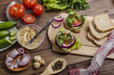 Tahtaya humus konmuş vejetaryen sandviçler ve ahşap kaplamalı malzemeler. Reklam için, menü.