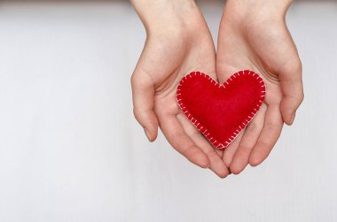 El yapımı kırmızı kalp, beyaz arka planda fotokopi alanı olan bir kızın ellerinde. Sevgililer Günü, Anneler Günü
