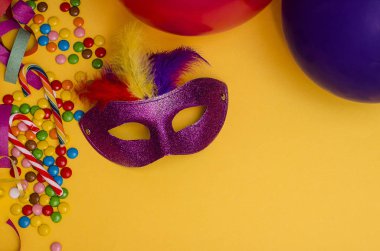 Karnaval. Fotokopi alanı olan şenlikli bir arka plan. Karnaval maskesi mor, sarı arka planda tüyleri var. Süslü, çok renkli şekerleri var. Mardi Gras 'da. Brezilya Dili.