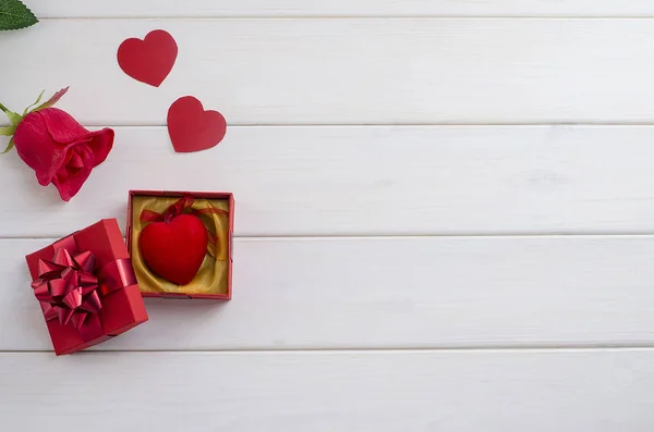 Gift for Valentine\'s Day, Mother\'s Day. Heart in a gift box with  a red bow with a rose with copy space on a white wooden background. Holiday Sale