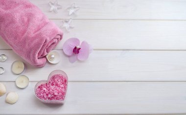 Sevgililer Günü hediyesi olarak spa tedavisi. Çiçekli pembe havlu, kabuklu deniz tuzu ve beyaz ahşap arka planda kopyalanmış kalp şeklinde pembe deniz tuzu. Güzellik salonu