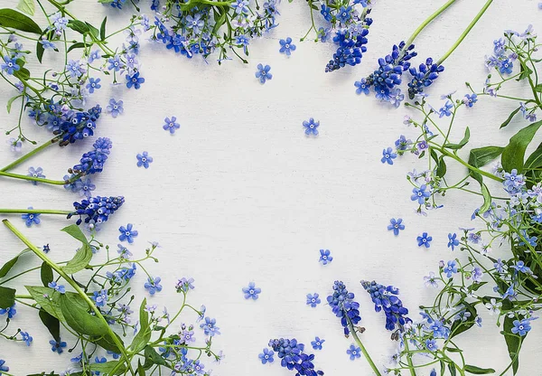 Frame of blue flowers with copy space on a white wooden background. Flower arrangement