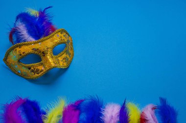 Karnaval. Fotokopi alanı olan şenlikli bir arka plan. Mavi arka planda renkli tüyleri olan altın karnaval maskesi. Mardi Gras 'da. Brezilya Dili. 