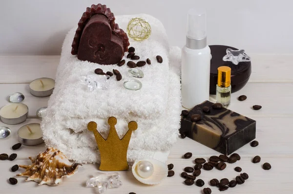 Royal chocolate and coffee spa treatment, massage as a gift. White towel, candle in the form of a heart, coffee beans, coffee soap, oil as a decor with copy space on a white background. Anti-stress and detox treatments. For beauty salons.