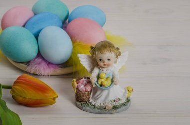 Paskalya kartı geçmişi. Renkli yumurtaları ve tavukları olan beyaz ahşap arka planda fotokopi alanı olan bir Paskalya meleği. Mutlu Paskalyalar. Yan görünüm.