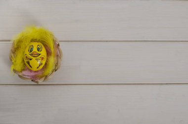 Paskalya kartı geçmişi. Beyaz ahşap arka planda tavuk şeklinde bir Paskalya yumurtası. Fotokopi alanı olan bir yuvada. Mutlu Paskalyalar. Düz yatıyordu.