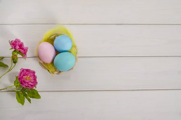 Easter card background. Easter multi-colored eggs on a white wooden background with a flowers with copy space. Happy easter. Flat lay. View from above.