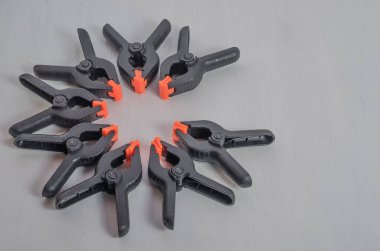 Beyaz arka planda siyah ve turuncu kıskaçlar. Orta boy plastik şarjörler. Marangozluk için klemp aletleri. Dikiş için el aletleri. Kıskaç ekipmanı.