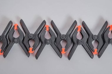 Beyaz arka planda siyah ve turuncu kıskaçlar. Orta boy plastik şarjörler. Marangozluk için klemp aletleri. Dikiş için el aletleri. Kıskaç ekipmanı.