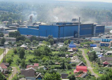 Dağdan eve, oradan da fabrikaya bakın. Çalışan bitki, buhar ve duman. Ekoloji, çevre ve atık sorunları.