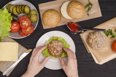 Adım adım ev yapımı bir hamburger pişiriyorum. Beşinci adım. Köfteleri salatanın üzerine sosla seriyorum. Düz yat. Reklam için..