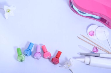 Manikür ve aksesuarları kurutmak için beyaz arka planda çok renkli ojeler ve lamba. Güzellik konsepti. Manikür teması. Düz yatıyordu.