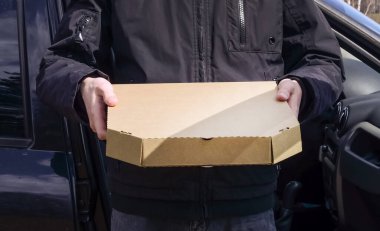 Kurye pizzayı arabayla teslim etti. Yemek servisi. Teslimatçı. Koronavirüs karantinası sırasında güvenli teslimat.
