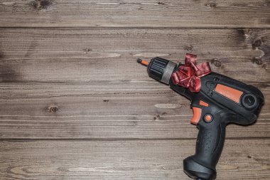 Tatil hediyesi olarak kırmızı kurdeleli bir tornavida. Babalar Günü, 23 Şubat, erkekler bayramı, yeni yıl ve Noel. Koyu bir ahşap arka planda.