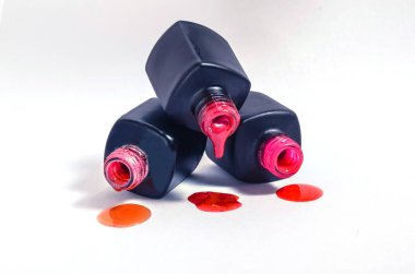 Beyaz arka planda izole edilmiş siyah şişelerden dökülen çok renkli ojeler. Kozmetik reklamı. Katalog için..