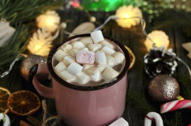 Beyaz seramik bardakta kremalı sıcak kakao, ahşap bir masanın üzerinde kış eşyalarıyla çevrili. Sıcak tatiller ve yeni yıl konsepti. Kış havası..