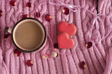 Bir fincan kakao ve örülmüş pembe arka planda şekerlemeler Sevgililer Günü için kalpli kurabiyeler. Anneler Günü. Aşk konsepti. en üstteki görünüm