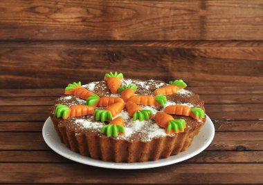 carrot cake with walnuts, Apple . against a dark wood background. Decorated with small carrots.  With a piece cut off.  piece of cake. piece of cake