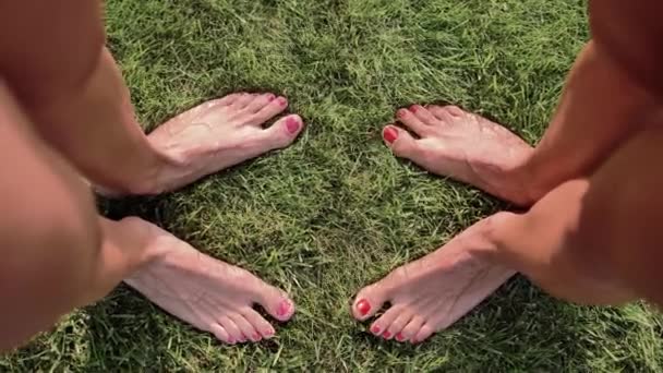 两只长着粉色和红色钉子的雌性脚 相对立在绿草上 扭动着手指 俯瞰前方 — 图库视频影像