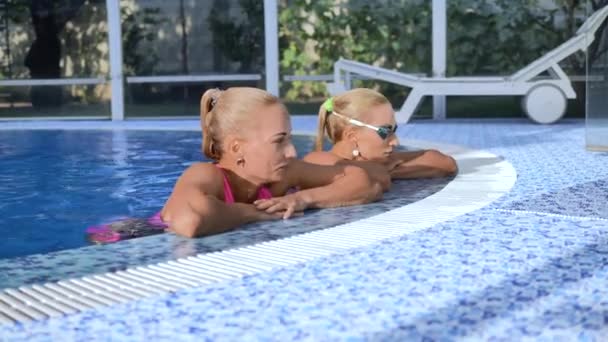 Twee Tweelingblondjes Roze Zwemkleding Zwemmen Een Zwembad Van Blauw Water — Stockvideo