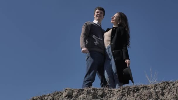 若いカップルの丘の上に 背景に青空 晴れた春の日に立つ — ストック動画