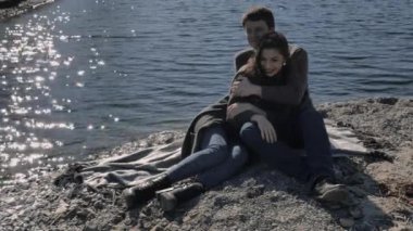 Date of a young couple on the river bank, in the background sun glare, sunny spring day