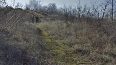 Young couple running from the hill holding hands, sunny spring day.