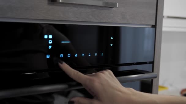 Main féminine ajuste les paramètres nécessaires dans le four, gros plan .