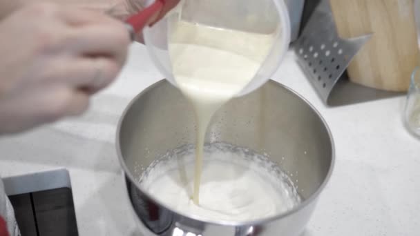 Les mains féminines versent du lait liquide dans une base blanche dans une tasse en métal, gros plan .