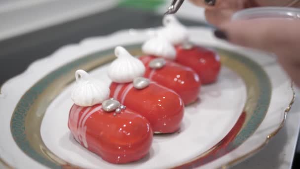 Een Vrouwelijke Hand Versierd Rode Desserts Met Witte Strepen Meringues — Stockvideo
