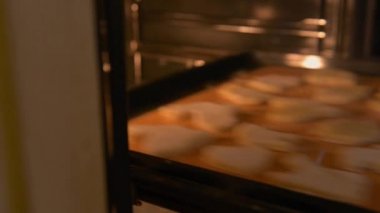 Pembe tırnaklı kadın elleri fırına kurabiye tepsisi koydu, yakın plan..