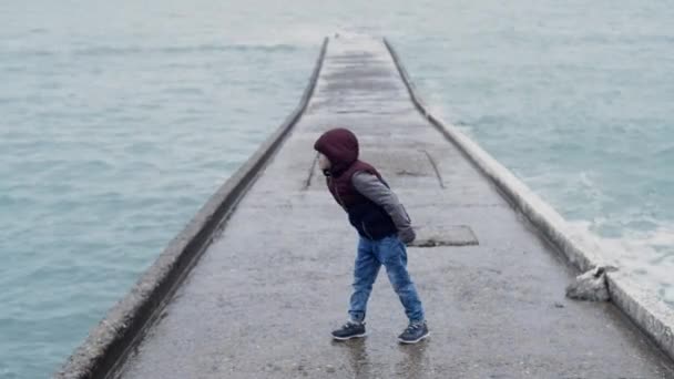 Bir Çocuk Beton Bir Binadan Mavi Deniz Suyuna Taş Atıyor — Stok video