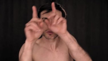 Beyaz bir adam kameranın önünde siyah bir arka planda dans ediyor..