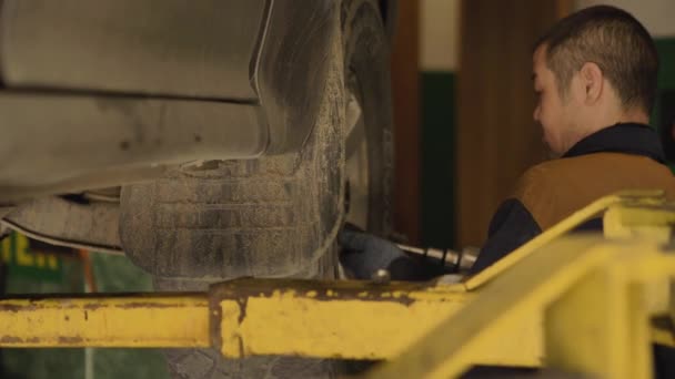 Ein Asiatischer Mann Repariert Einer Werkstatt Großaufnahme Das Fahrgestell Eines — Stockvideo