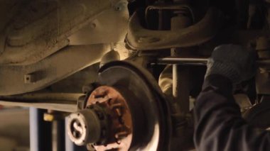 Eldivenli eller ve iş kıyafetleri garajda bir arabanın yedek parçasını tamir ediyor, yakın plan..