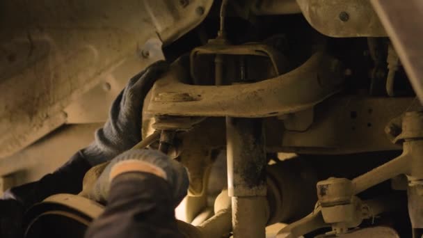 戴着手套和穿着工作服的人正在修车库里修理汽车的零件 — 图库视频影像