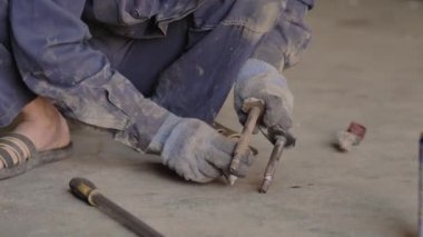 Eldivenli ve iş elbiseli Asyalı garajda yedek parça tamir ediyor, yakın plan..