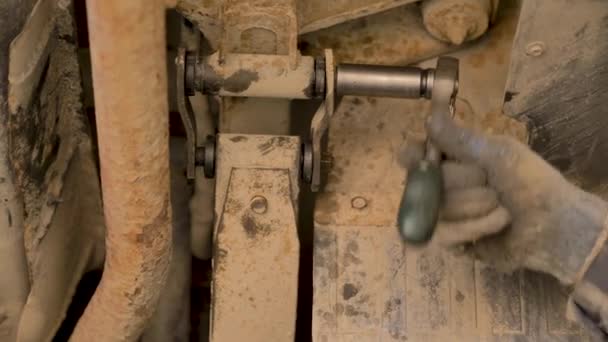 Les mains dans les gants et les vêtements de travail sont en train de réparer une pièce de rechange d'une voiture dans un garage, gros plan .