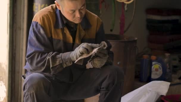 身着手套和工作服的亚洲人正在修车库里的零件 — 图库视频影像