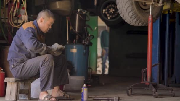 Ασιάτης Γάντια Και Ρούχα Εργασίας Επισκευάζει Ένα Ανταλλακτικό Του Αυτοκινήτου — Αρχείο Βίντεο